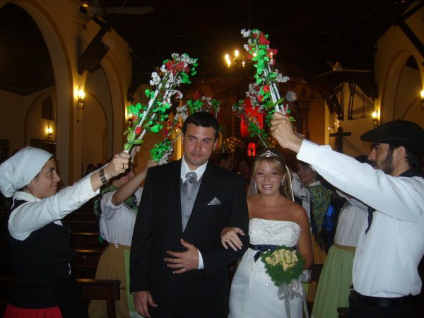 Los novios, ya marido y mujer, salen de la iglesia al término de la ceremonia bajo los arcos de los dantzaris